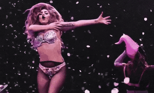 a woman in a bra and panties is dancing on a stage in front of confetti falling from the sky .