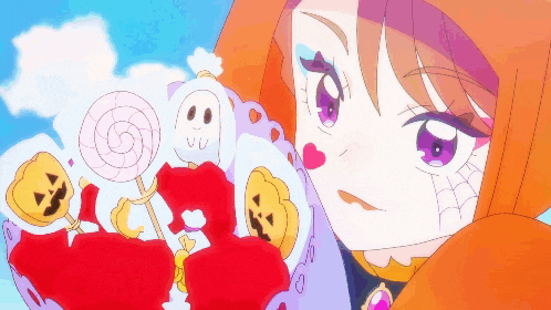 a girl in an orange hood is holding a lollipop with a face on it