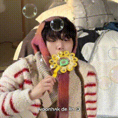 a young boy is blowing soap bubbles while wearing a flower shaped toy .