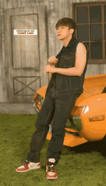 a young man leans against an orange car with a sign that says entertainment talent candy land