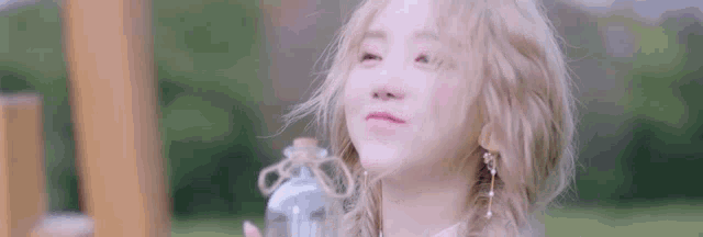 a woman is holding a bottle of water in her hand and making a funny face .
