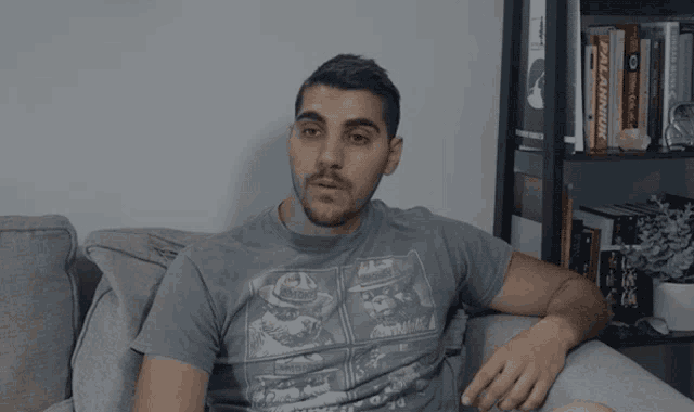 a man is sitting on a couch wearing a t-shirt that says " pro wrestling "