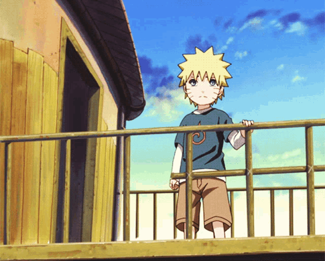 a young boy stands on a balcony wearing a blue shirt with the letter a on it