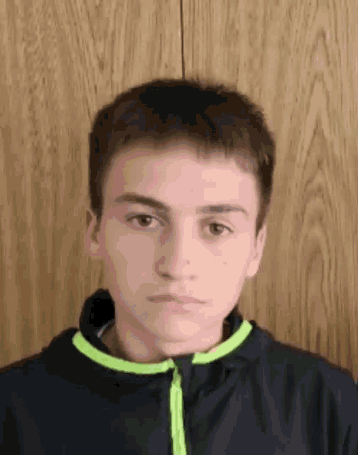a young boy is wearing a black jacket with a green stripe around the neck .