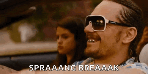a man wearing sunglasses is driving a car with a girl in the background .