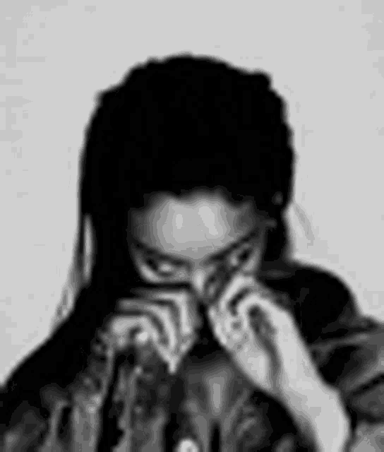 a black and white photo of a woman wearing glasses and covering her face .