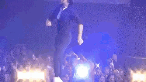 a man is dancing on a stage in front of a crowd of people