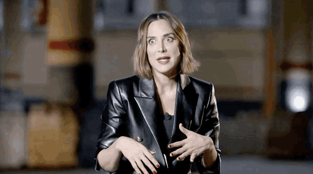 a woman is wearing a black leather jacket and making a funny face .