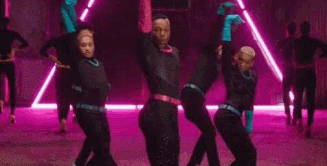 a group of men are dancing in front of a pink light