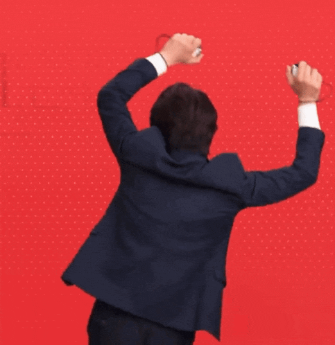 a man in a suit is raising his arms in the air