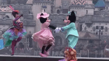 mickey mouse and minnie mouse are dancing in front of a castle