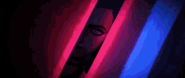 a woman 's face is peeking out from behind a purple and pink light