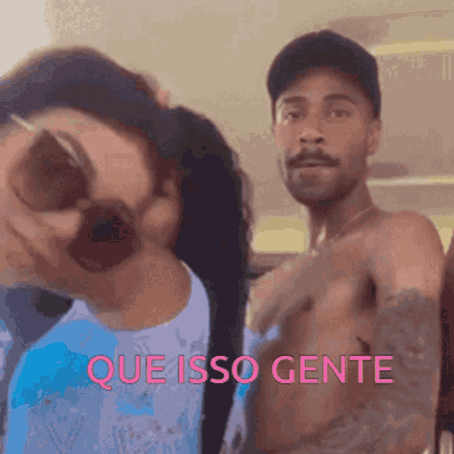 a man without a shirt is standing next to a woman wearing sunglasses and the words que isso gente are above him