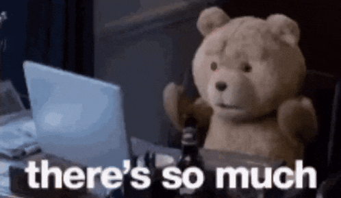 a teddy bear is sitting at a desk in front of a laptop computer and says there 's so much .