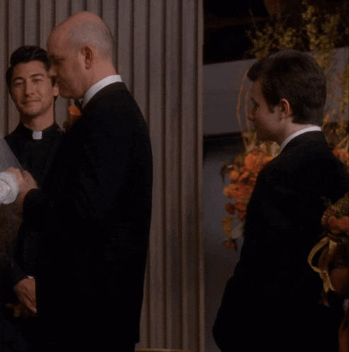 a man in a tuxedo holds the hand of a woman