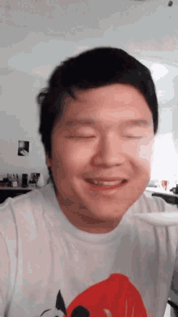 a man is smiling with his eyes closed and wearing a white shirt