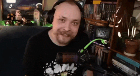 a man wearing headphones and a t-shirt that says bubbles is sitting in front of a microphone .