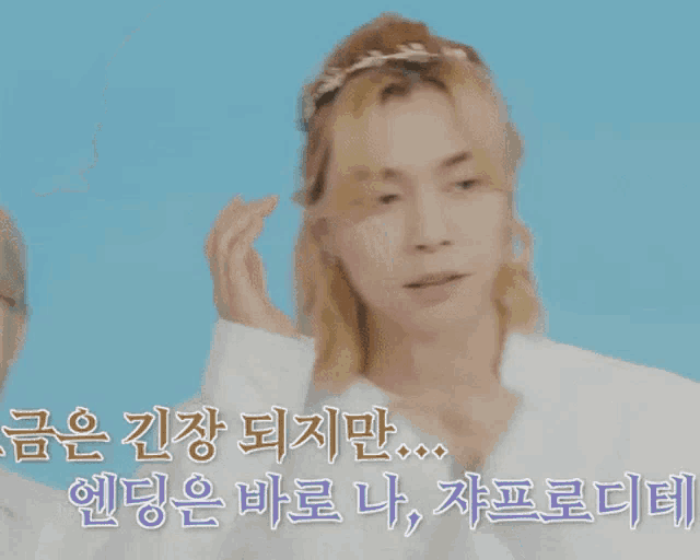 a man wearing a white shirt and a gold headband holds his hands to his ears