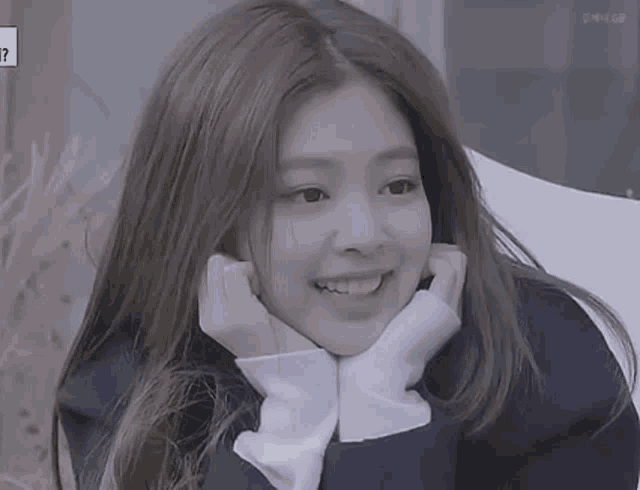 a close up of a girl with her hands on her face and smiling .