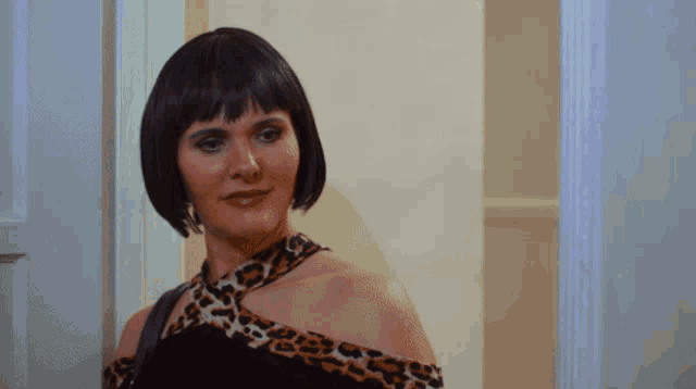 a woman in a black and leopard print dress stands in a doorway