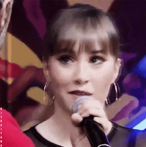 a close up of a woman singing into a microphone with the letter a visible in the corner