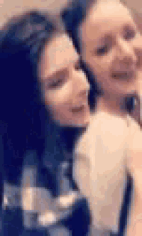two women are standing next to each other and smiling .