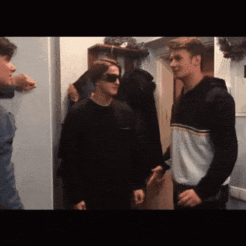 a man wearing sunglasses is talking to another man in a room .