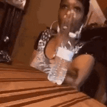 a woman is sitting at a table with a bottle of water .