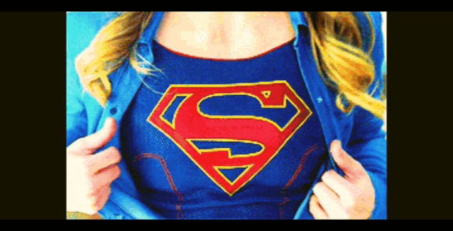 a woman is wearing a blue shirt with a red and gold superman logo on it