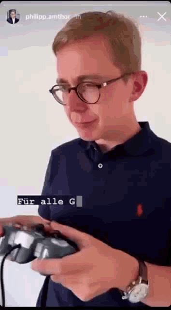 a man wearing glasses is holding a video game controller ..