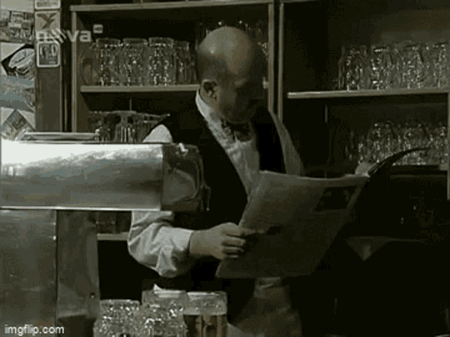 a bald man is reading a newspaper in a bar ..