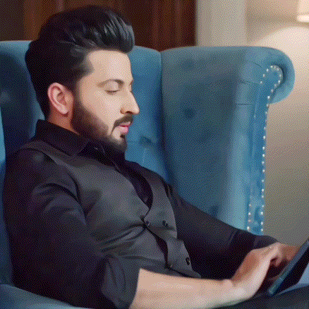 a man with a beard is sitting in a blue chair using a tablet .