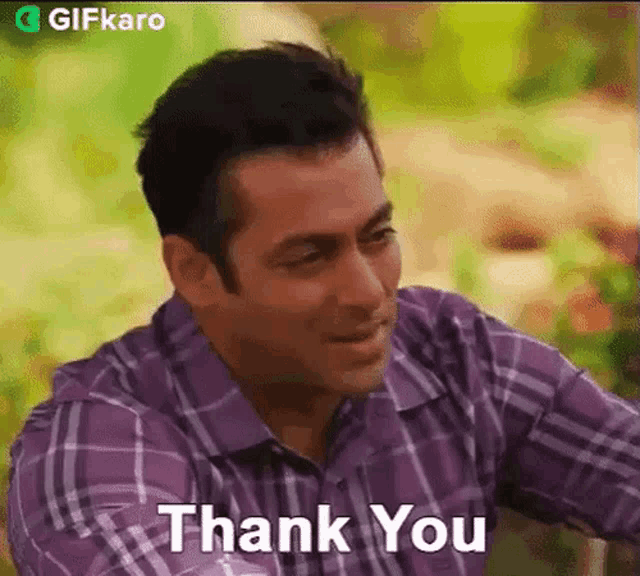 a man in a purple shirt is sitting down and saying thank you .