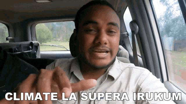 a man sitting in a car with the words " climate la supera irukum " above him