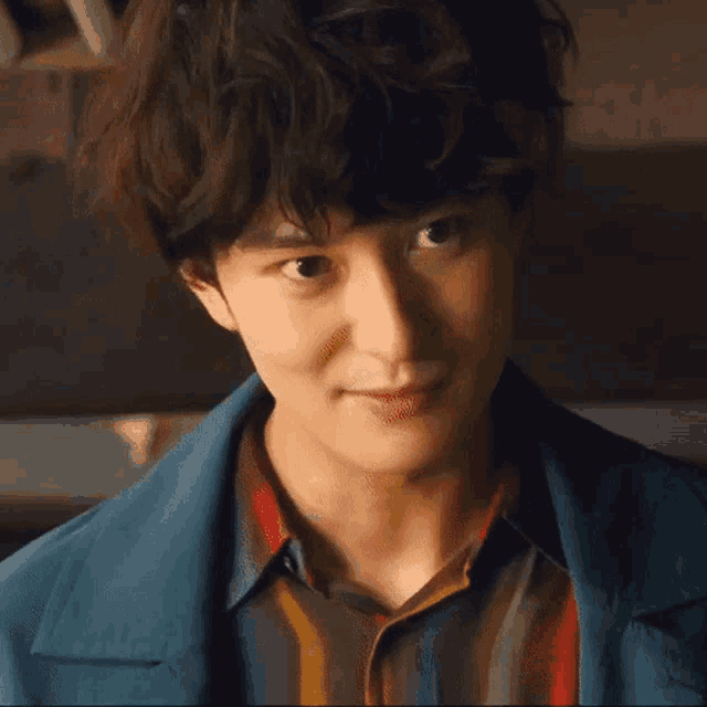 a close up of a young man 's face with a blue jacket and striped shirt .