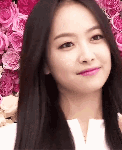 a close up of a woman 's face with pink roses in the background