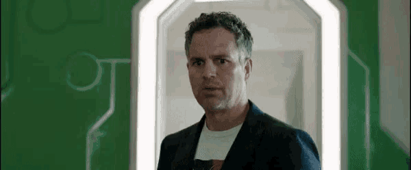 a man in a suit and white shirt is standing in a hallway .