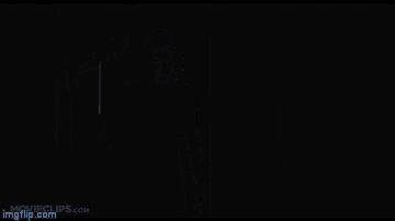 a man in a black suit is standing in the dark in a room .