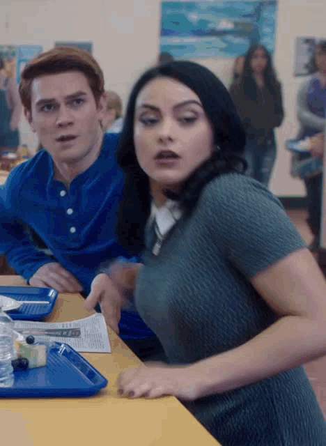 a man and a woman are sitting at a table with a blue tray