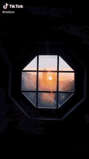 a tiktok video of a sunset through a window shows a lighthouse in the distance