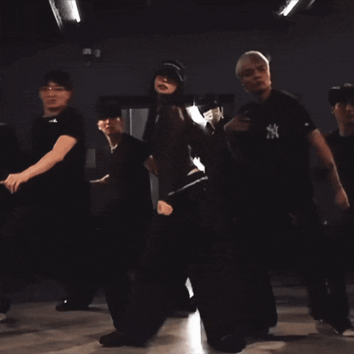 a group of people are dancing in a dark room with an exit sign above them