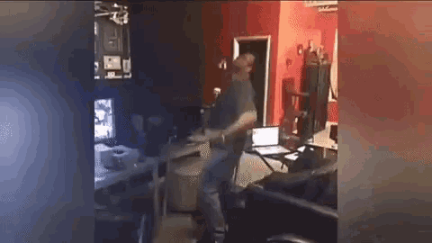 a man is dancing in a living room with a laptop on a table .