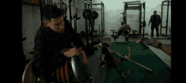 a group of men are fighting in a gym with a red barbell that says ' hammer ' on it