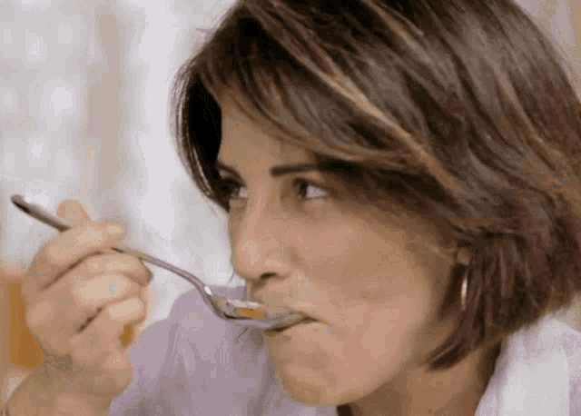 a woman is eating something with a spoon and making a funny face