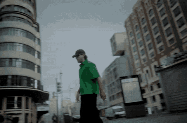 a man in a green shirt walks down a street