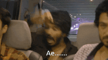 a man in a plaid shirt is driving a car with the word ae on the steering wheel