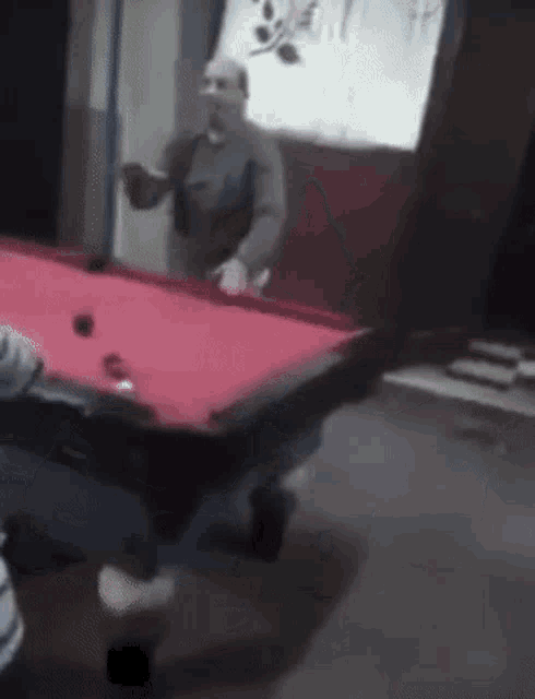a man is playing pool in a dark room with a red table