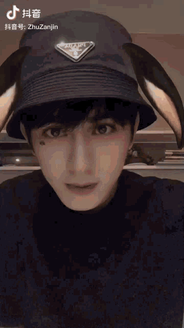 a young man wearing a black hat with a prada logo on it