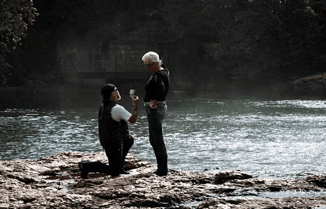 a man is proposing to a woman by the water