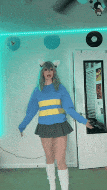 a girl in a blue sweater and gray skirt is dancing in front of a door